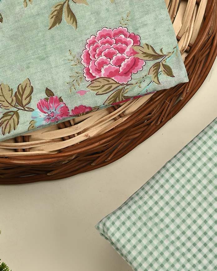 Floral fabric with pink flowers and green leaves on a woven basket and checkered fabric on a neutral background.